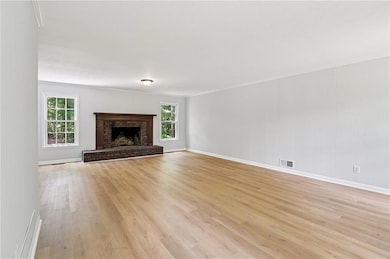 Unfurnished living room featuring light wood-style flooring, baseboards, and a fireplace