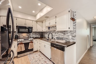 Kitchen featuring black appliances, a sink, dark c