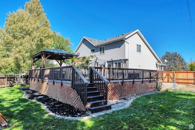 Back of house with a fenced backyard, a gazebo, a wooden deck, and a gate