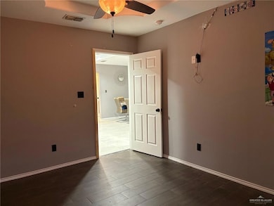Empty room with a ceiling fan, dark wood finished floors, and baseboards