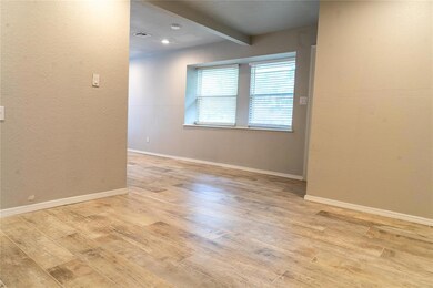 Empty room with light wood Living room with wood look tile finished floors, beam ceiling, baseboards, and a textured wall