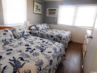 Bedroom featuring dark wood-style floors, a wainscoted wall, and a wall mounted air conditioner
