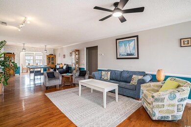 Living room featuring a textured ceiling, wood finished floors, crown molding, and wallpapered walls