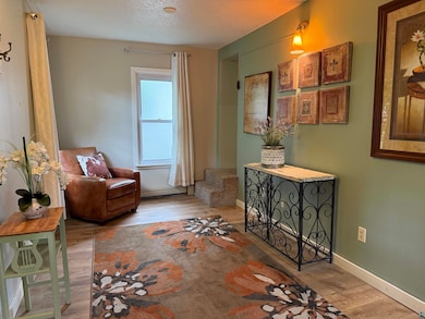 Living area with wood finished floors, a textured ceiling, and a baseboard heating unit