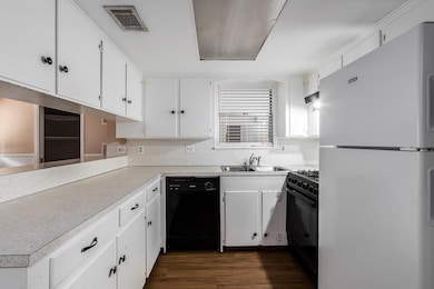 Kitchen featuring black appliances, light counter