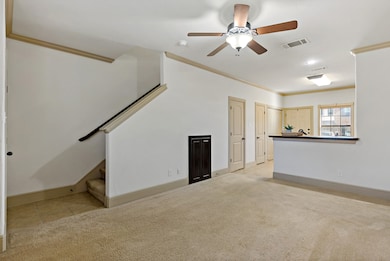 Unfurnished living room with light carpet, crown molding, stairs, ceiling fan, and light tile patterned floors