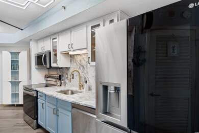 Kitchen featuring white cabinetry, tasteful backsp