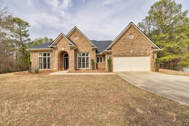 View of front facade with a front yard, brick siding, driveway, and an attached garage