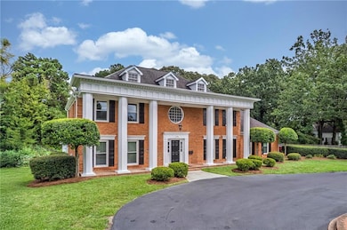 Greek revival house with a porch, a front lawn, and brick siding