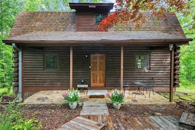 View of front facade featuring log siding, roof with shingles, and a porch