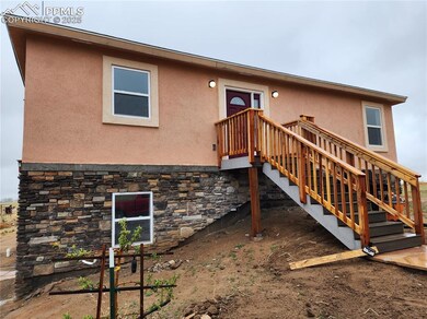 Rear view of property featuring stone siding and stucco siding