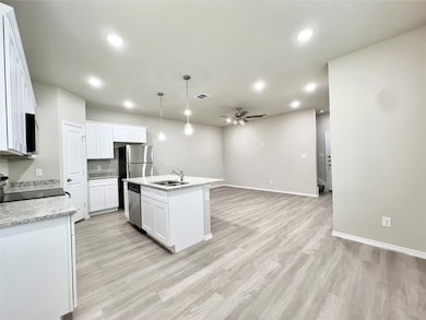 Kitchen featuring pendant lighting, a kitchen island with sink, recessed lighting, light wood-type flooring, and open floor plan