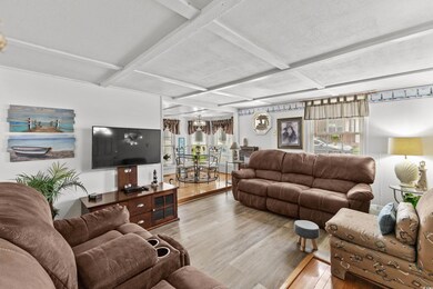 Living room featuring wood finished floors, coffered ceiling, plenty of natural light, and beam ceiling