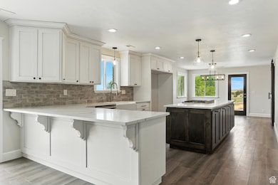 Kitchen featuring backsplash, light stone counters, a kitchen breakfast bar, a center island, and white cabinetry