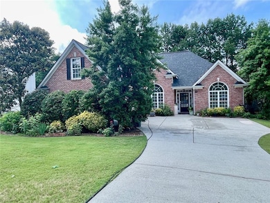 Traditional-style home featuring brick siding, a front yard, and a shingled roof