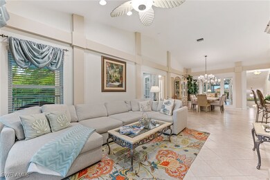 Living area with a chandelier, light tile patterned flooring, ceiling fan, and high vaulted ceiling