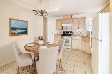 Kitchen featuring freestanding refrigerator, decorative backsplash, stainless steel electric range, light tile patterned floors, and pendant lighting