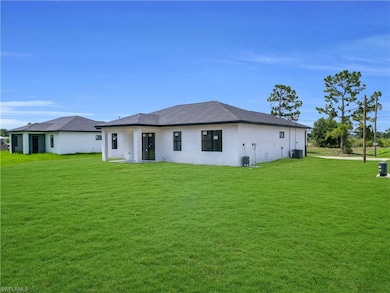 Rear view of house featuring a yard, stucco siding, and central AC
