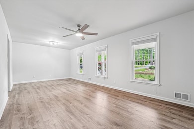 Empty room featuring baseboards, visible vents, ceiling fan, and light wood-style floors