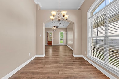 Unfurnished dining area with arched walkways, a chandelier, ornamental molding, and dark wood-type flooring