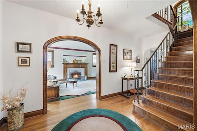 Entrance foyer featuring arched doorways, hardwood floors & steps with wrought iron rail.