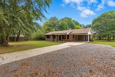Ranch-style home featuring driveway, brick siding, an attached carport, and a shingled roof