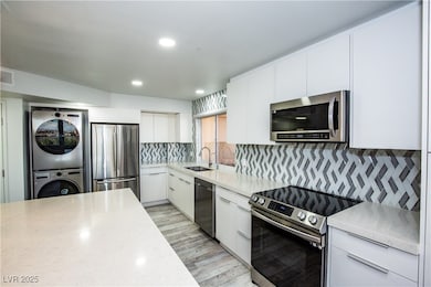 Kitchen with a sink, light countertops, stacked wa