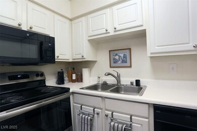 Kitchen featuring black appliances, light countertops, and white cabinets