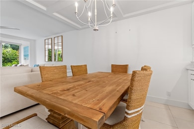 Tiled dining room featuring beamed ceiling, coffered ceiling, and a chandelier