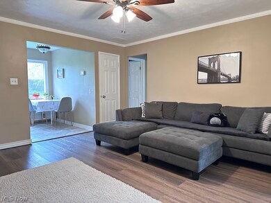 Living room with hardwood / wood-style floors, ceiling fan, and crown molding