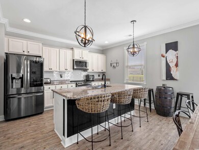 Kitchen with white cabinets, an island with sink, sink, a chandelier, and stainless steel appliances