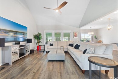 Living room with wood finished floors, a chandelier, high vaulted ceiling, and ceiling fan