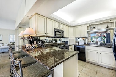 Kitchen featuring kitchen peninsula, dark stone counters, black appliances, and light tile patterned floors