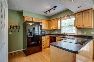 Kitchen features include black appliances, updated lighting, and hardwood floors.