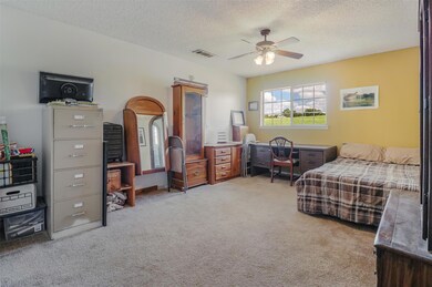 Bedroom with ceiling fan, light carpet, and a text