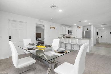 Dining space with light carpet, visible vents, lig