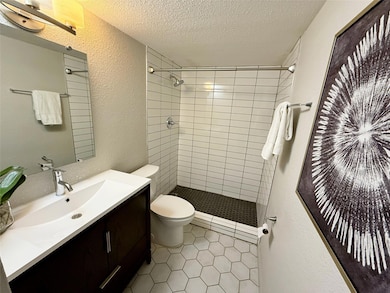 Bathroom with a textured wall, a textured ceiling