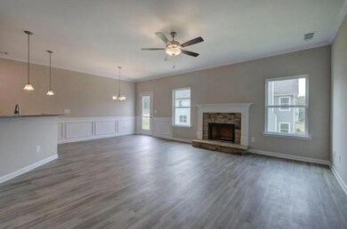 Unfurnished living room featuring a ceiling fan, dark wood-style flooring, a chandelier, a stone fireplace, and baseboards