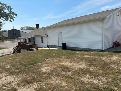 Rear view of house featuring a wooden deck and a yard