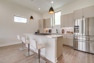 Kitchen with stainless steel appliances, decorative backsplash, a breakfast bar, decorative light fixtures, and large island