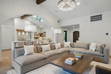 Living area featuring arched walkways, beamed cei