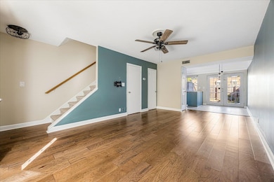 Unfurnished living room featuring french doors, stairway, wood finished floors, and ceiling fan