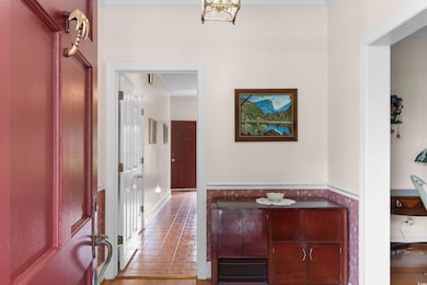 Hallway with ornamental molding, light wood-style floors, and wainscoting