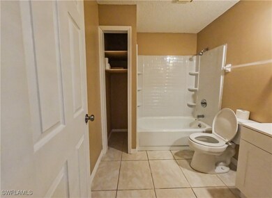 Full bathroom with a textured ceiling, toilet, til
