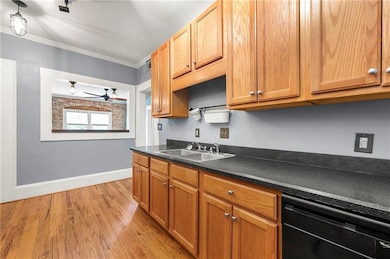 Kitchen with black dishwasher, a sink, ornamental molding, dark countertops, and a ceiling fan