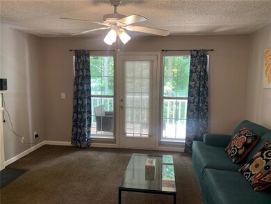 Living area with a textured ceiling, healthy amount of natural light, a ceiling fan, and dark colored carpet