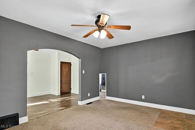 Spare room with arched walkways, carpet, and ceiling fan
