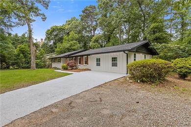 Ranch-style house featuring board and batten siding, concrete driveway, and a front lawn