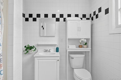Bathroom with tile walls, vanity, and a shower with shower curtain