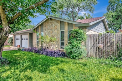 View of side of property with an attached garage, stone siding, and driveway
